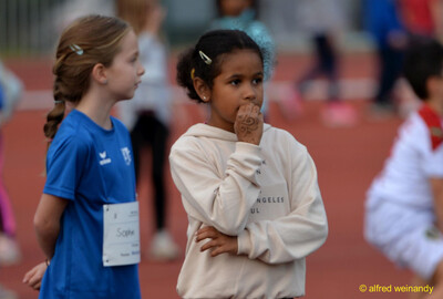 Zwei Kinder stehen nebeneinander und unterhalten sich am Rand der Laufbahn beim Jugendsportfest der TG Konz in Konz