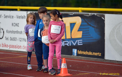 Vier Kinder mit Startnummern stehen wartend hinter einem orangen Kegel auf der Laufbahn beim Jugendsportfest der TG Konz in Konz