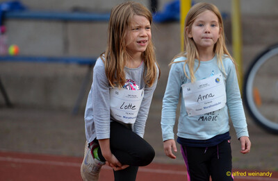 Zwei Kinder wärmen sich auf der Laufbahn auf, ein Kind dehnt dabei das Bein, beim Jugendsportfest der TG Konz in Konz.