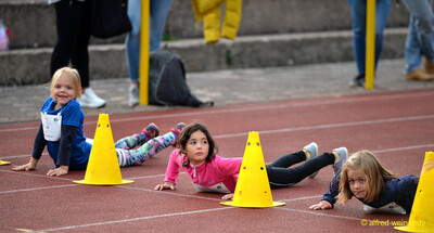 Mehrere Kinder liegen auf der Laufbahn und meistern eine Geschicklichkeitsübung an gelben Pylonen beim Jugendsportfest der TG Konz in Konz.
