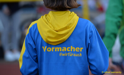 Rückenansicht einer Person in blau-gelber Vereinsjacke mit einer Aufschrift beim Jugendsportfest der TG Konz in Konz.