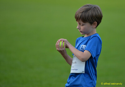 Ein Kind hält einen Schlagball in den Händen und bereitet sich auf den Wurf vor beim Jugendsportfest der TG Konz in Konz.