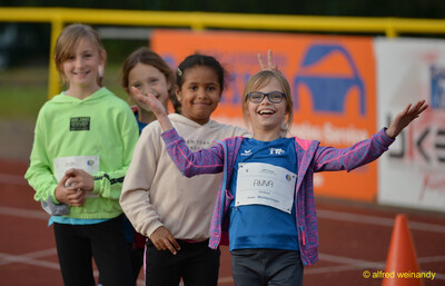 Lächelnde Kindergruppe posiert mit erhobenen Armen beim Jugendsportfest der TG Konz in Konz.