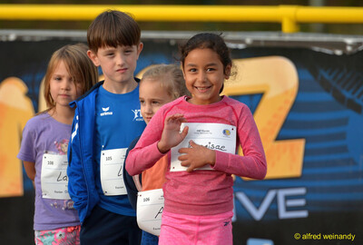 Gruppe von Kindern mit Startnummern posiert vor einer Bande beim Jugendsportfest der TG Konz in Konz.