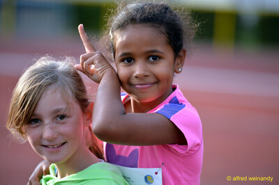Zwei Kinder posieren lächelnd vor der Laufbahn beim Jugendsportfest der TG Konz in Konz.