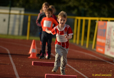Ein Kind läuft beim Hindernislauf an niedrigen Schaumstoff-Hürden auf der Laufbahn vorbei beim Jugendsportfest der TG Konz in Konz.