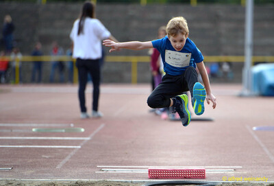 Ein Kind springt vom Absprungbalken in die Weitsprunggrube beim Jugendsportfest der TG Konz in Konz.