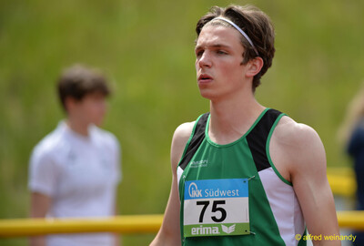 Eine junge Person im grün-schwarzen Trikot mit Stirnband und Startnummer 75 steht auf dem Sportgelände, bei der Rheinland-Pfalz-Meisterschaft in Konz.