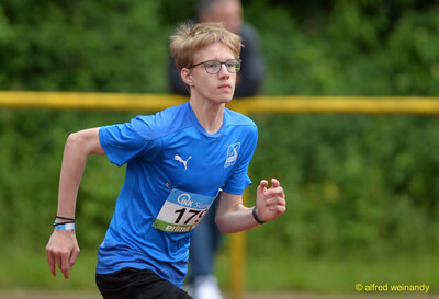 Eine junge Person mit Brille im blauen Trikot in Laufbewegung mit konzentriertem Blick, bei der Rheinland-Pfalz-Meisterschaft in Konz.