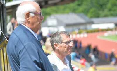 Zwei Personen beobachten vom Rand der Tribüne aus das Geschehen im Stadion bei der Rheinland-Pfalz-Meisterschaft in Konz.
