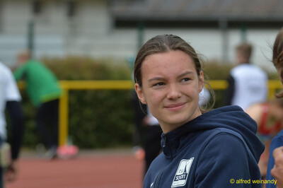 Porträt einer lächelnden jugendlichen Person in dunkelblauem Vereinshoodie auf der Sportanlage bei der Rheinland-Pfalz-Meisterschaft in Konz.