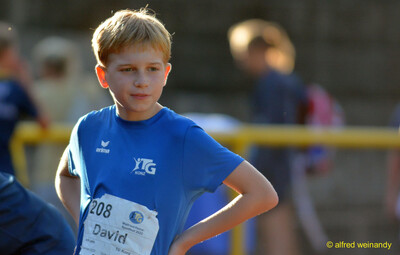 Ein Kind der TG Konz mit Startnummer steht mit den Händen in der Hüfte beim Walfried-Heinz-Sportfest der TG Konz im Saar-Mosel-Stadion in Konz.