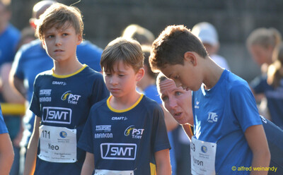 Drei Kinder mit Startnummern stehen mit der Übungsleitung zusammen beim Walfried-Heinz-Sportfest der TG Konz im Saar-Mosel-Stadion in Konz.