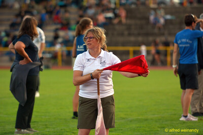 Eine Person im Kampfgericht mit roter Fahne auf dem Rasen beim Walfried-Heinz-Sportfest der TG Konz im Saar-Mosel-Stadion in Konz.