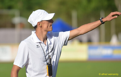 Eine Person im Kampfgericht gibt mit ausgestrecktem Arm ein Zeichen beim Walfried-Heinz-Sportfest der TG Konz im Saar-Mosel-Stadion in Konz.