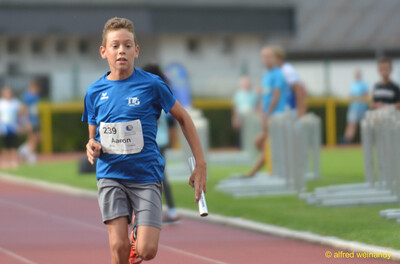 Ein Kind läuft mit dem Staffelstab im Staffellauf beim Walfried-Heinz-Sportfest der TG Konz im Saar-Mosel-Stadion in Konz.