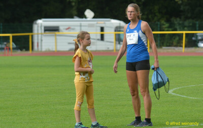 Eine Person steht mit einem Kind auf dem Rasen im Stadion beim Walfried-Heinz-Sportfest der TG Konz im Saar-Mosel-Stadion in Konz.