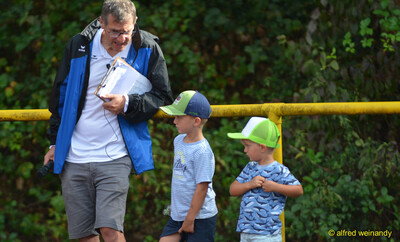 Die Moderation spricht per Mikrofon mit zwei Kindern am Rand der Bahn beim Walfried-Heinz-Sportfest der TG Konz im Saar-Mosel-Stadion in Konz.
