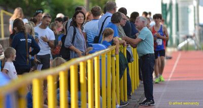 Zuschauende stehen an der Absperrung neben der Laufbahn beim Walfried-Heinz-Sportfest der TG Konz im Saar-Mosel-Stadion in Konz.