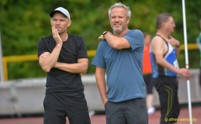 Zwei Personen beobachten das Geschehen am Rand der Anlage beim Walfried-Heinz-Sportfest der TG Konz im Saar-Mosel-Stadion in Konz.