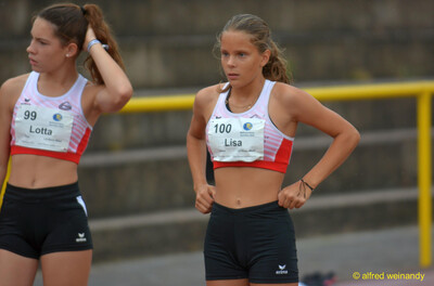 Zwei Jugendliche mit Startnummern warten in Wettkampfkleidung beim Walfried-Heinz-Sportfest der TG Konz im Saar-Mosel-Stadion in Konz.