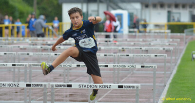 Ein Kind springt in der Flugphase über eine Hürde beim Walfried-Heinz-Sportfest der TG Konz im Saar-Mosel-Stadion in Konz.