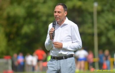 Eine Person hält eine Rede mit dem Mikrofon beim Walfried-Heinz-Sportfest der TG Konz im Saar-Mosel-Stadion in Konz.