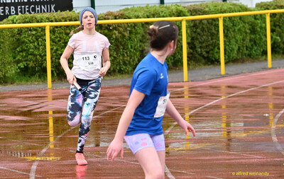 Eine Person nähert sich mit dem Staffelstab in der Hand einer wartenden Person im Team beim Walfried-Heinz-Sportfest der TG Konz im Saar-Mosel-Stadion in Konz.