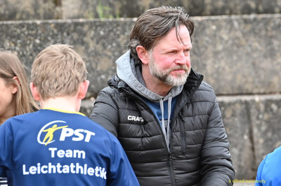 Eine betreuende Person steht neben einem Kind am Rand der Anlage beim Walfried-Heinz-Sportfest der TG Konz im Saar-Mosel-Stadion in Konz.