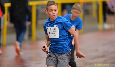 Ein Kind sprintet mit dem Staffelstab in der Hand beim Walfried-Heinz-Sportfest der TG Konz im Saar-Mosel-Stadion in Konz.