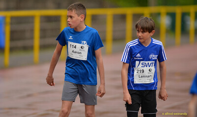 Zwei Kinder mit Startnummern gehen nebeneinander über die Bahn beim Walfried-Heinz-Sportfest der TG Konz im Saar-Mosel-Stadion in Konz.