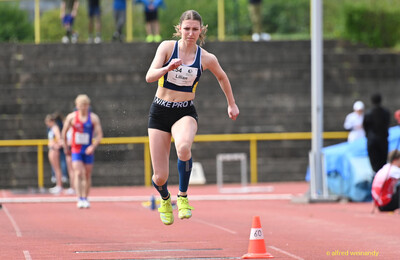 Eine Person fliegt in einer Sprungphase des Dreisprungs über die Anlaufbahn beim Walfried-Heinz-Sportfest der TG Konz im Saar-Mosel-Stadion in Konz.