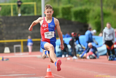 Eine Person springt in der Schrittphase des Dreisprungs über die Anlaufbahn beim Walfried-Heinz-Sportfest der TG Konz im Saar-Mosel-Stadion in Konz.