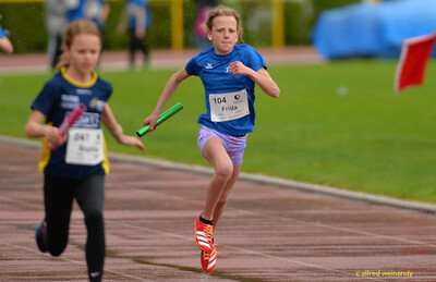 Zwei Kinder sprinten mit Staffelstäben über die Rundbahn beim Walfried-Heinz-Sportfest der TG Konz im Saar-Mosel-Stadion in Konz.