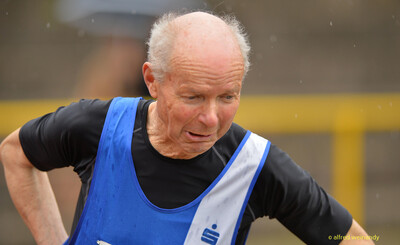 Nahaufnahme einer älteren Person im blauen Singlet, die sich mit den Händen in die Hüften stützt, beim Walfried-Heinz-Sportfest der TG Konz im Saar-Mosel-Stadion in Konz.
