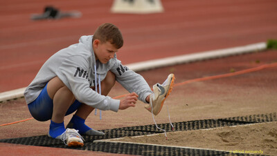 Ein Kind zieht am Rand der Weitsprung-Sandgrube seine Spikes an beim Walfried-Heinz-Sportfest der TG Konz im Saar-Mosel-Stadion in Konz.
