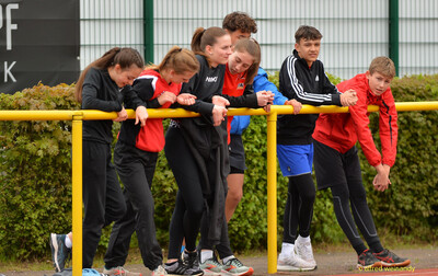 Eine Gruppe Jugendlicher lehnt an der Absperrung und beobachtet das Geschehen beim Walfried-Heinz-Sportfest der TG Konz im Saar-Mosel-Stadion in Konz.