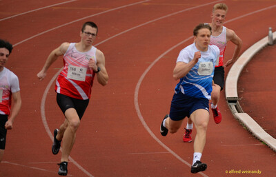 Mehrere Aktive sprinten dicht beieinander durch die Kurve der Laufbahn beim Walfried-Heinz-Sportfest der TG Konz im Saar-Mosel-Stadion in Konz.