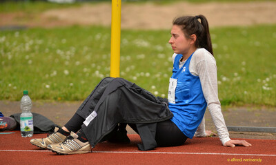Eine Person sitzt in einer Pause auf der Bahn beim Walfried-Heinz-Sportfest der TG Konz im Saar-Mosel-Stadion in Konz.