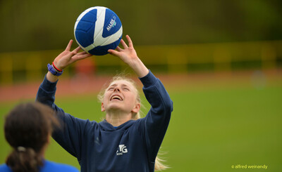 Ein Kind fängt beim Aufwärmen mit angehobenen Armen einen Ball beim Walfried-Heinz-Sportfest der TG Konz im Saar-Mosel-Stadion in Konz.