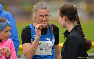 Eine Person im TG-Konz-Trikot mit Startnummer unterhält sich mit einer jüngeren Person beim Walfried-Heinz-Sportfest der TG Konz im Saar-Mosel-Stadion in Konz