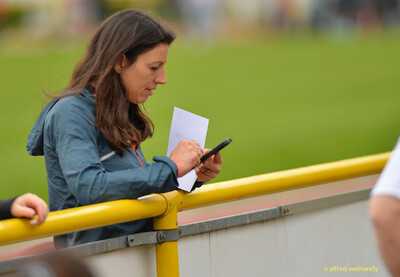 Eine Person notiert am Geländer etwas auf dem Smartphone und hält ein Blatt Papier beim Walfried-Heinz-Sportfest der TG Konz im Saar-Mosel-Stadion in Konz