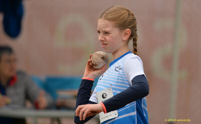 Ein Kind legt die Kugel in Stoßstellung an den Hals im Kugelstoßen beim Walfried-Heinz-Sportfest der TG Konz im Saar-Mosel-Stadion in Konz.