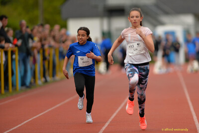 Zwei Kinder sprinten Seite an Seite auf der Bahn beim Walfried-Heinz-Sportfest der TG Konz im Saar-Mosel-Stadion in Konz.