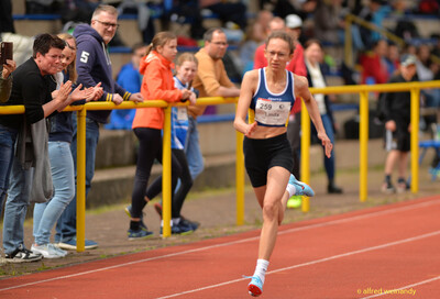 Eine Person sprintet auf der Rundbahn am applaudierenden Publikum vorbei beim Walfried-Heinz-Sportfest der TG Konz im Saar-Mosel-Stadion in Konz.