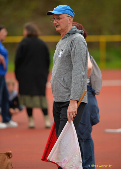 Eine Person im Kampfgericht mit Wimpel und Staffelstab steht auf der Bahn beim Walfried-Heinz-Sportfest der TG Konz im Saar-Mosel-Stadion in Konz.