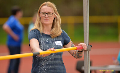 Eine Person im Kampfgericht legt die Hochsprunglatte in die Ständer beim Walfried-Heinz-Sportfest der TG Konz im Saar-Mosel-Stadion in Konz.