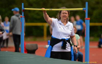 Eine Person im Kampfgericht legt die Latte auf die Hochsprung-Ständer auf beim Walfried-Heinz-Sportfest der TG Konz im Saar-Mosel-Stadion in Konz.