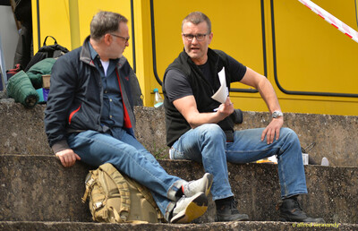 Zwei Personen sitzen im Gespräch auf den Stufen der Tribüne beim Walfried-Heinz-Sportfest der TG Konz im Saar-Mosel-Stadion in Konz.