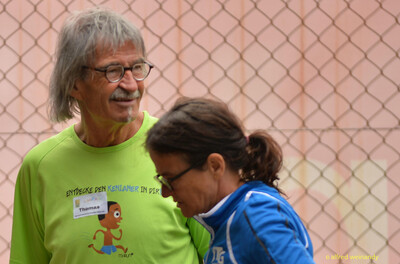 Zwei Personen unterhalten sich am Rand des Sportgeländes bei der Rheinland-Meisterschaft im Mehrkampf der TG Konz in Konz.